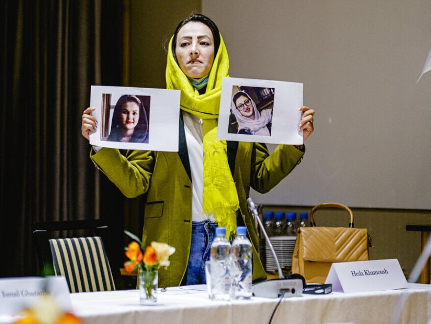 Delegate from the Afghan civil society Heda Khamoush holds up photos of two women who have vanished, ahead of a meeting, in Oslo, Norway, Monday, Jan. 24, 2022.