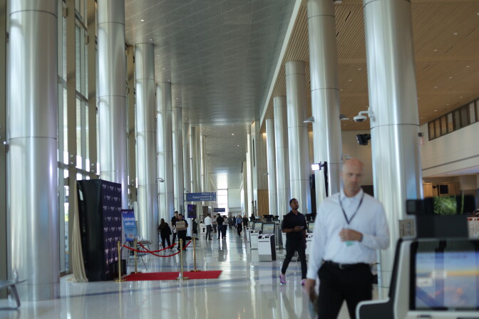 A wide view across the large terminal that looks down a row of tall white multiple columns. People are walking in the frame. The ceiling is high up.
