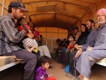 In this Thursday, Sept. 10, 2015 photo,  Syrian refugees sit in a Jordanian army vehicle after crossing into Jordanian territory with their families, in the Roqban reception area, near the northeastern Jordanian border with Syria, and Iraq, near the town of Ruwaished, 240 km (149 miles) east of Amman. The United Nations' refugee agency has urged Jordan to speed up security vetting for Syrian refugees, who must wait for weeks in a remote desert area during the process. (AP Photo/Raad Adayleh)
