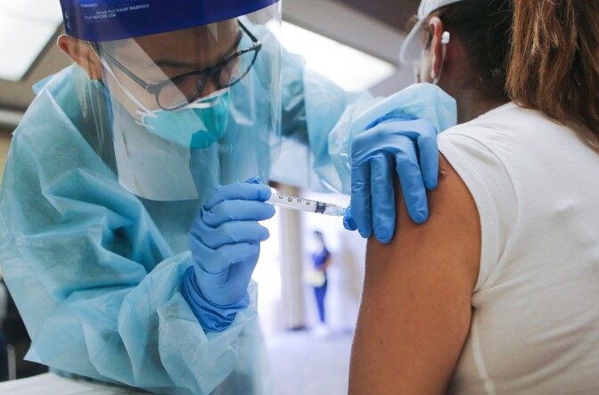 LAKEWOOD, CALIFORNIA - OCTOBER 14: A nurse administers a flu vaccination shot to a woman at a free clinic held at a local library on October 14, 2020 in Lakewood, California. Medical experts are hoping the flu shot this year will help prevent a ‘twindemic’- an epidemic of influenza paired with a second wave of COVID-19 which could lead to overwhelmed hospitals amid the coronavirus pandemic. (Photo by Mario Tama/Getty Images)