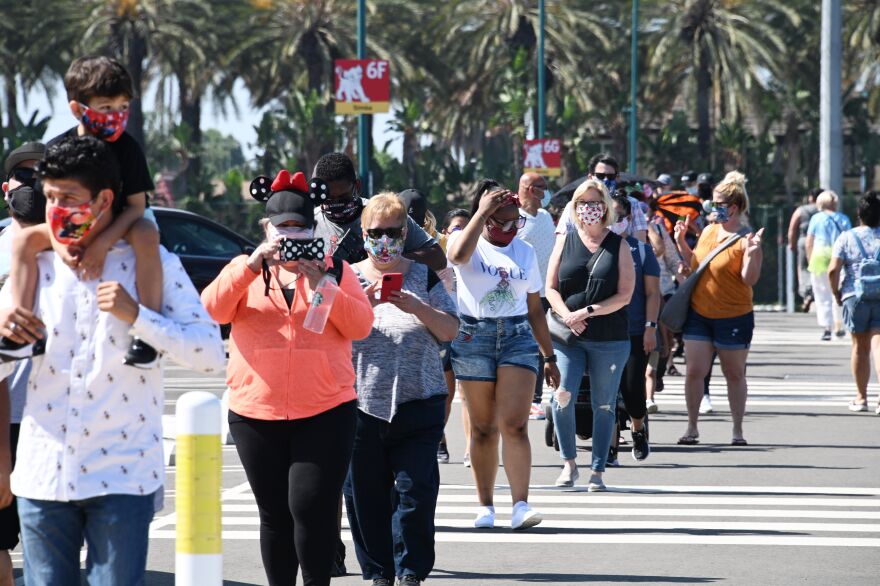 People wait in line to enter Downtown Disney in Anaheim, California on July 9, 2020, the first day the outdoor shopping and dining complex has been open to the public since it closed in mid-March amid the COVID-19 pandemic. - Disney's California theme park reopening may have been thwarted by coronavirus, but hundreds lined up early July 9, 2020 to buy Mickey Mouse merchandise from an adjacent shopping plaza. Downtown Disney District -- which borders the world-famous Disneyland and Disney California Adventure theme parks near Los Angeles -- is the first part of the sprawling resort to reopen. (Photo by Robyn Beck / AFP) (Photo by ROBYN BECK/AFP via Getty Images)