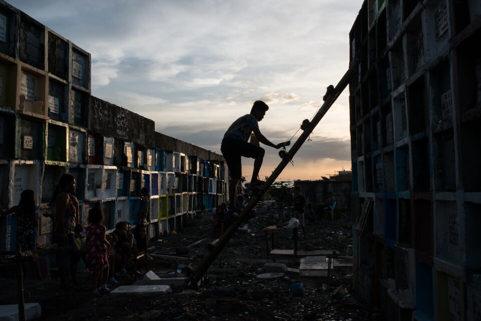 A man climbs on a ladder to reach a tombstone at a public cemetery on November 1, 2016 in Manila, Philippines. In the Philippines, family members clean tombs and often spend the night at the cemetery eating and celebrating with loved ones.