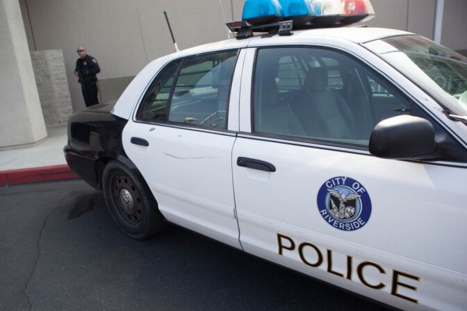 A police cruiser is parked outside a police department in Riverside. The department was heavily secured by guards with automatic weapons.