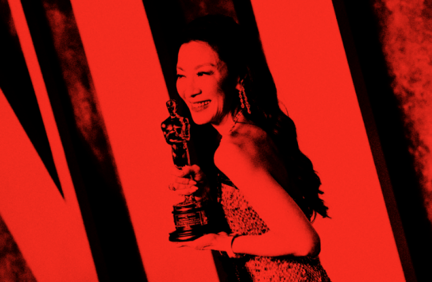 Oscar winner Michelle Yeoh poses with her Oscar. She smiles at the camera and holds her Oscar up in ¾ profile. There is a red filter over the image to indicate that it is part of the Academy Museum Podcast series.