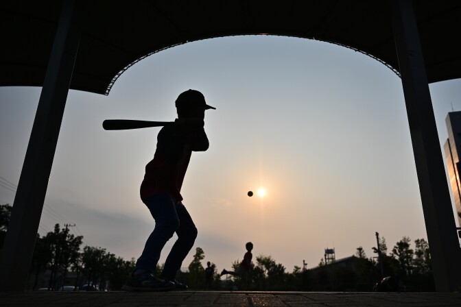 Boys play a game of baseball in Kosuge in Tokyo on April 22, 2019. (Photo by CHARLY TRIBALLEAU / AFP)        (Photo credit should read CHARLY TRIBALLEAU/AFP/Getty Images)