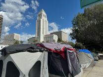 Tents line a sidewalk in front of a tall white building.