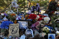 A memorial for an eagle named Jackie features flowers, flags, photos, pinecones and a sign reading "Queen Jackie 2012-2026."