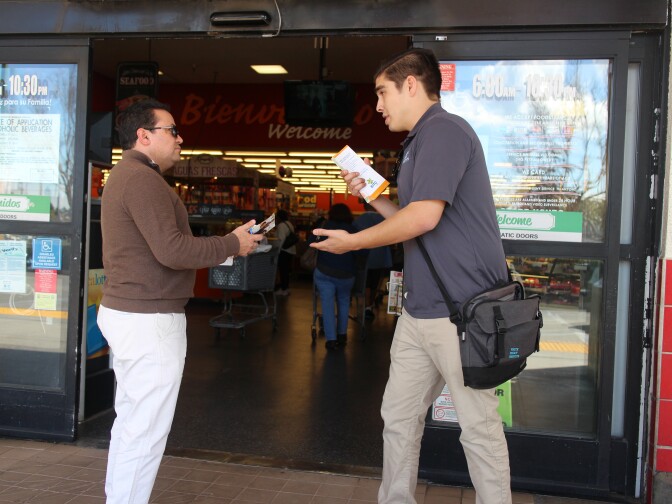 Matthew Fontana, a promotor with the Youth Policy Institute, talks with a shopper outside of the Northgate Market in Culver City. 
