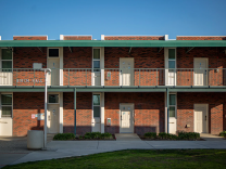 A two-story building features white doors and brick walls.