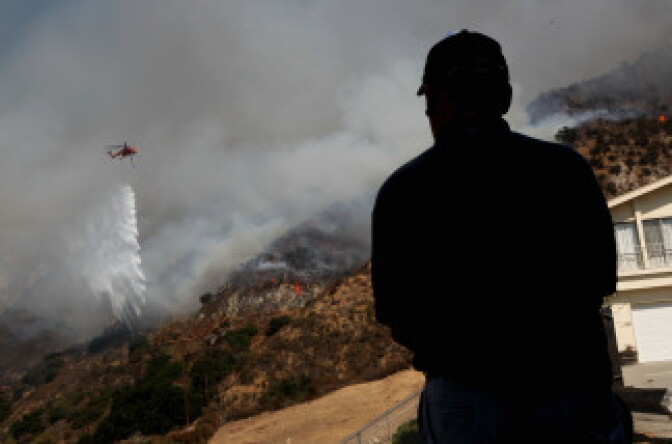 A local resident watches a firefighting helicopter drop water ahead of the Station Fire as it approaches homes August 31, 2009 in Tujunga, California. 