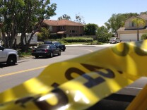 Police tape closes a street where four people were found dead in a home, center, on Tuesday, May 27, 2014 in suburban Mission Viejo.