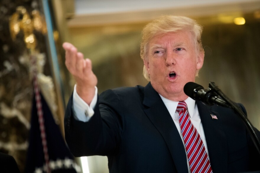 Former President Donald Trump speaks at a podium and gestures with his right hand.