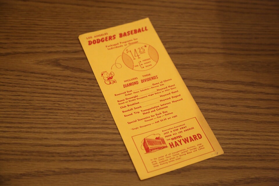 A bright yellow tri-fold brochure with red lettering sits on a brown wooden table top. 