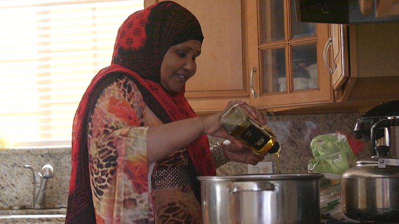 Mariam Ali, a Somali refugee who lives in San Diego's Teralta neighborhood, pours olive oil into a pot for alfredo sauce, Feb. 26, 2016.