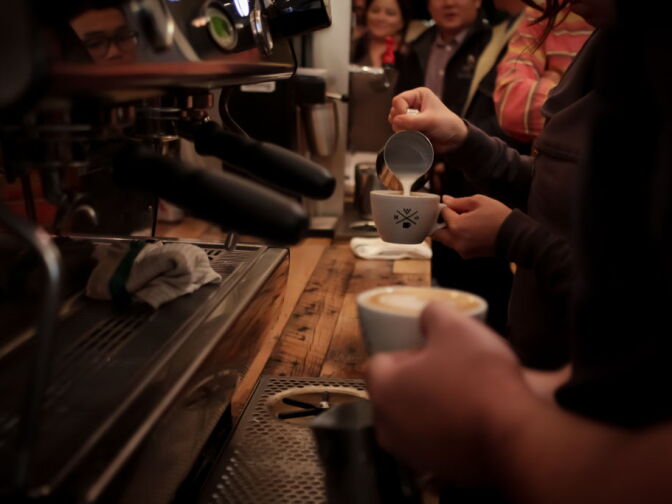 Competitors pour steamed milk into espresso to make latte art.