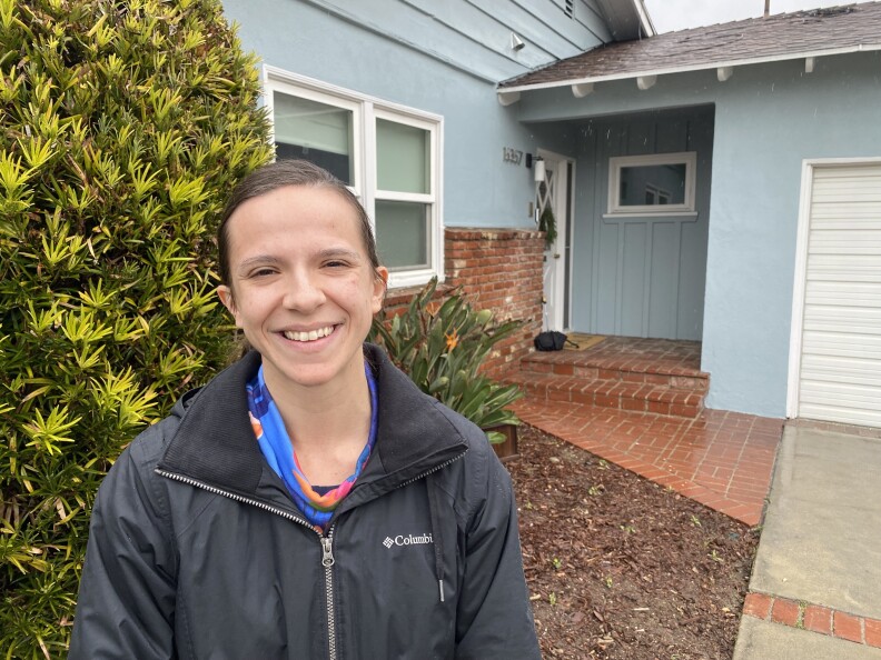 Sara Steffan, dressed in a rain jacket and smiling, stands near the front porch of her house in Van Nuys.