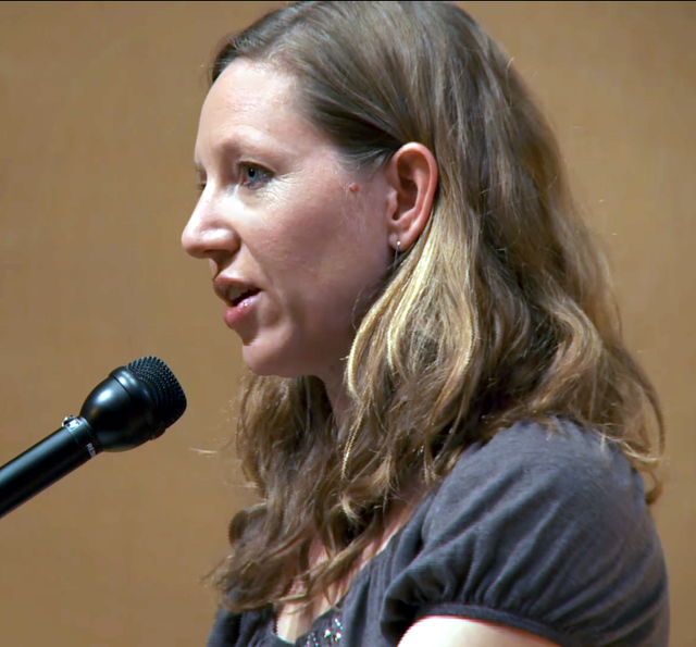 Author Maggie Nelson speaks into a microphone.