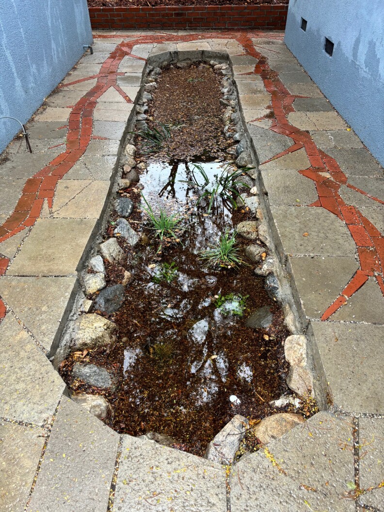 A hole in concrete with rocks in it.