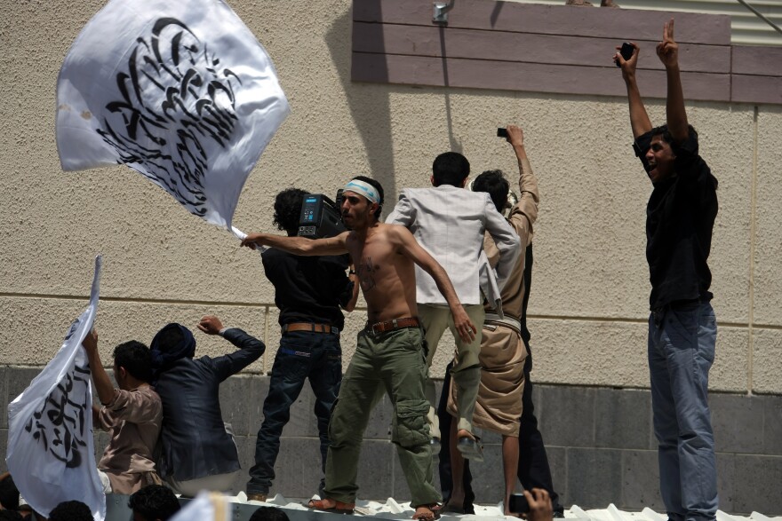 A Yemeni protester waves a flag bearing Islamic calligraphy outside the gate of the US embassy in Sanaa during a protest over a film mocking Islam on September 13, 2012. 