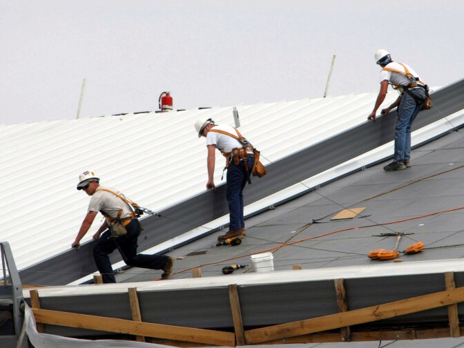 Workers install a cool roof. Usually white or light colored, they can be up to 55 degrees cooler than regular roofs. 