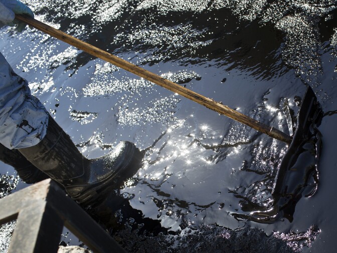 Crews clean up the remains of about 10,000 gallons of crude oil that sprayed into Los Angeles streets and onto buildings early Thursday morning, May 15 after a high-pressure pipe burst.