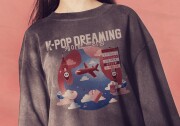 A person wears a sweatshirt with the words K-POP DREAMING -- also in Korean -- with an image of the globe showing a plane flying between LAX and South Korea. 