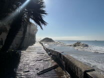 A flooded boardwalk along a coastline with eroded sand berms.