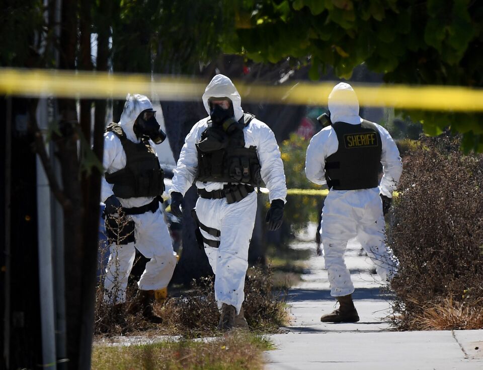 Members of the Los Angeles County Sheriff's Department bomb and hazmat squad, search a house where a large amount of military ordnance including artillery shells and grenades was found in Lawndale, California on September 29, 2017. 
Up to 100 local residents were evacuated to a nearby school, during the 14 hour operation to remove the ordnance from the residential property and one person was arrested in the raid. / AFP PHOTO / Mark RALSTON        (Photo credit should read MARK RALSTON/AFP/Getty Images)