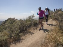 People hike along a ridge where vegetation quickly dried out in Griffith Park on March 29, 2015 in Los Angeles, California during a record-breaking heat wave.