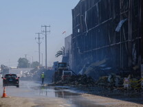Crews clean up debris from a burned building.