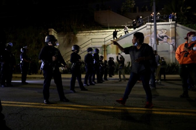 A resident of the park who identified themselves as "The Queen" speaks to a line of LAPD officers lined up on Glendale Blvd. (Brian Feinzimer for LAist)