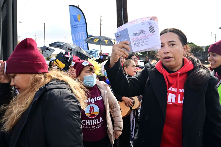 A diverse group of voters crowds outdoors, several wearing CHIRLA shirts.