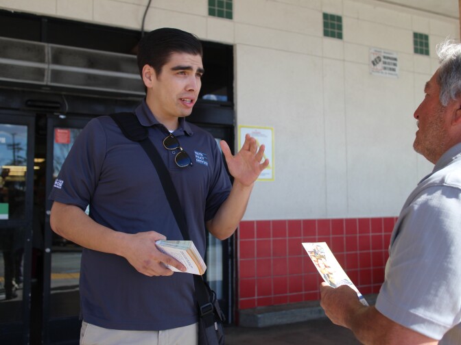 Matthew Fontana, a promotor with the Youth Policy Institute, talks with a shopper outside of the Northgate Market in Culver City. 