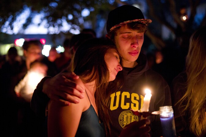Two students comfort each other during a candlelight vigil held to honor the victims of Friday night's mass shooting on Saturday, May 24, 2014, in Isla Vista, Calif. Sheriff's officials said Elliot Rodger, 22, went on a rampage near the University of California, Santa Barbara, stabbing three people to death at his apartment before shooting and killing three more in a crime spree through a nearby neighborhood. (AP Photo/Jae C. Hong)