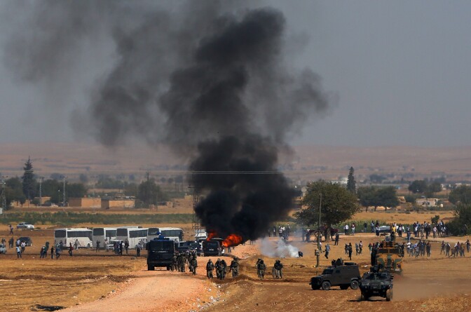 A car hit by a teargas canister burns as riot police use teargas to disperse Kurdish demonsrators as thousands of Syrian refugees continue to arrive at the border in Suruc, Turkey, Monday, Sept. 22, 2014. Some 130,000 Syrian refugees fleeing the advance of Islamic State militants have crossed the border into Turkey in the past four days, Turkey's deputy prime minister said Monday, warning that the number could rise further as the militants continue their onslaught. (AP Photo/Burhan Ozbilici)