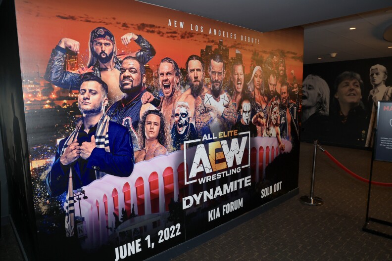 A large wall advertisement for All Elite Wrestling (AEW) making its Los Angeles debut in 2022 at the Kia Forum. It features numerous wrestlers of various races and an image of the round Forum with its column architecture, as well as the L.A. skyline.