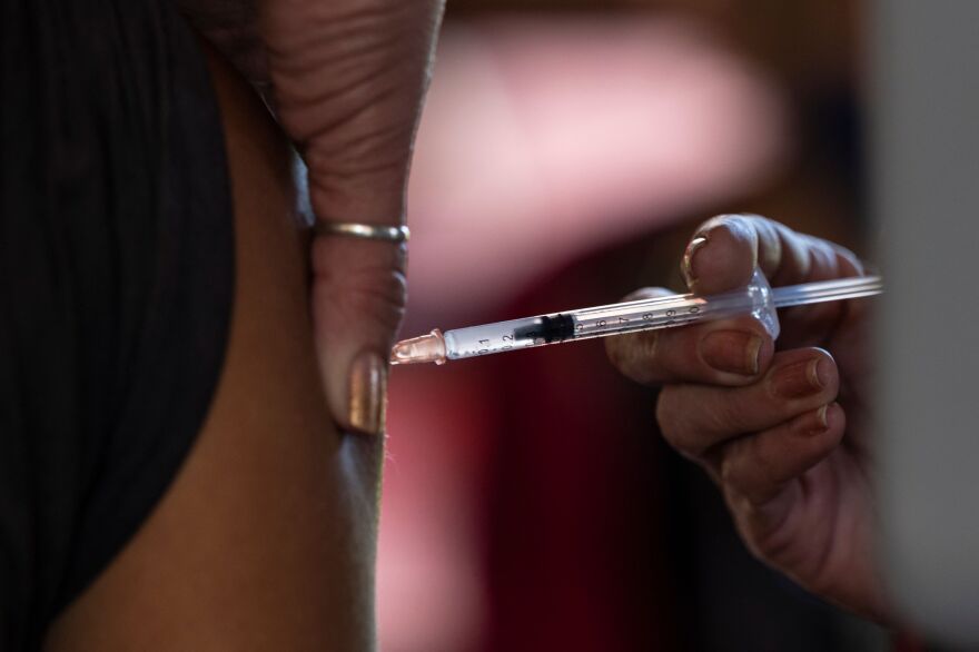 Closeup of someone squeezing the skin on a person's arm while injecting them with a shot.