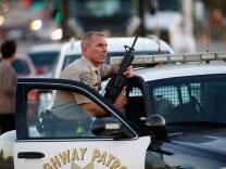 SAN BERNARDINO, CA - DECEMBER 02: A California Highway Patrol officer stands with his weapon as authorities pursued the suspects in a shooting that occurred at the Inland Regional Center on December 2, 2015 in San Bernardino, California.  Police continue to search for suspects in the shooting that left at least 14 people dead and another 17 injured.   (Photo by Sean M. Haffey/Getty Images)