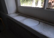 The outlines of plant pots are seen on a white window sill darkened by soot from the Eaton Fire. 