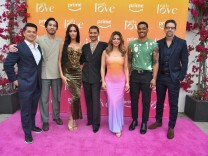 7 people stand side-by-side, a colorful backdrop is behind them with logos for Amazon Prime Video and the show "With Love."