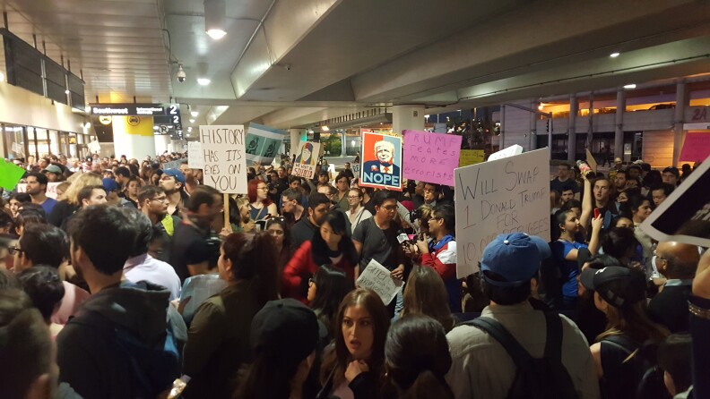 Protesters hold signs outside Terminal 2 at Los Angeles International Airport on Sunday, Jan. 29, 2017, amid calls to release immigrants detained under President Donald Trump's executive order effectively banning travel from seven majority Muslim nations.