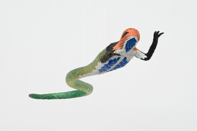 This photo features a suspended sculpture of a fantastical creature that blends elements of a bird and a snake.