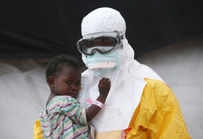 PAYNESVILLE, LIBERIA - OCTOBER 05:  A Doctors Without Borders (MSF), health worker in protective clothing holds a child suspected of having Ebola in the MSF treatment center on October 5, 2014 in Paynesville, Liberia. The girl and her mother, showing symptoms of the deadly disease, were awaiting test results for the virus. The Ebola epidemic has killed more than 3,400 people in West Africa, according to the World Health Organization.  (Photo by John Moore/Getty Images)