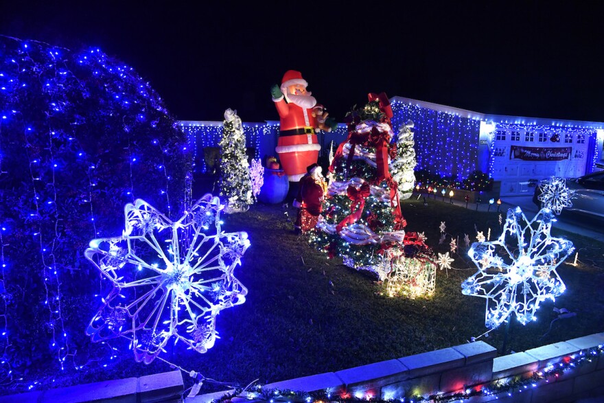 Illuminated stars, presents, trees and an inflatable Santa Claus on the front lawn of a house