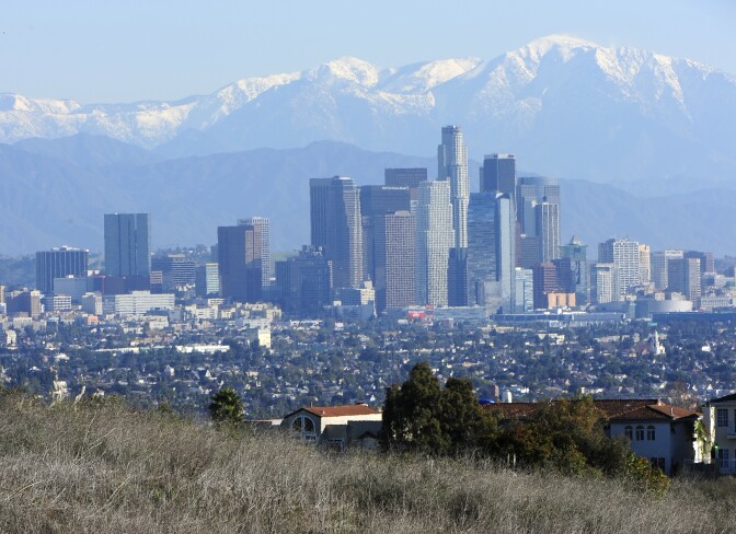 Against a background of the Los Angeles city skyline, a man pushes his bicycle up a hill in Kenneth Hahn State Recreation Area on December 31, 2010 in Los Angeles, California.  