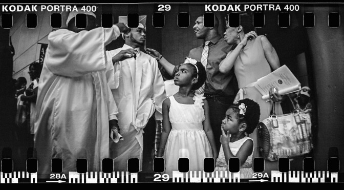 NEW ORLEANS, LA - MAY 14:  (This Image was made with a panoramic film camera and scanned into a black and white digital file) McDonogh #35 Senior High School graduate Malik Hayes (2nd L) stands with family and friends at his commencement at the Ernest N. Morial Convention Center on May 14, 2015 in New Orleans, Louisiana. Hayes' home was flooded during Hurricane Katrina when he was eight years old. Thousands of Hurricane Katrina survivors attempted to use the convention center as a shelter of last resort in the days following the storm, yet it lacked power, water, food and medical supplies. McDonogh 35 was damaged by flooding from Hurricane Katrina and was the first high school for African-Americans in the state of Louisiana. It is one of the last remaining traditional public schools in the city. The tenth anniversary of Hurricane Katrina, which killed at least 1836 and is considered the costliest natural disaster in U.S. history, is August 29. (Photo by Mario Tama/Getty Images)