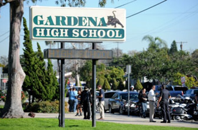 People walk past the entrance to Gardena High School in Gardena, California January 18, 2011 after two students were shot, one in the head, when a gun went off accidentally in a classroom.
