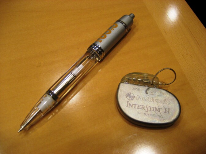The bladder pacemaker (right) is shown in relation to a pen. It is implanted in the buttocks and connected to a series of electrodes that are attached to the spine near nerves that go to the bladder.