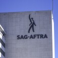 A multi-story stone facade building has SAG- AFTRA on its side with a figure gesturing to the sky