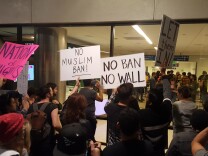 Protesters hold signs outside Terminal 2 at Los Angeles International Airport on Sunday, Jan. 29, 2017, amid calls to release immigrants detained under President Donald Trump's executive order effectively banning travel from seven majority Muslim nations.